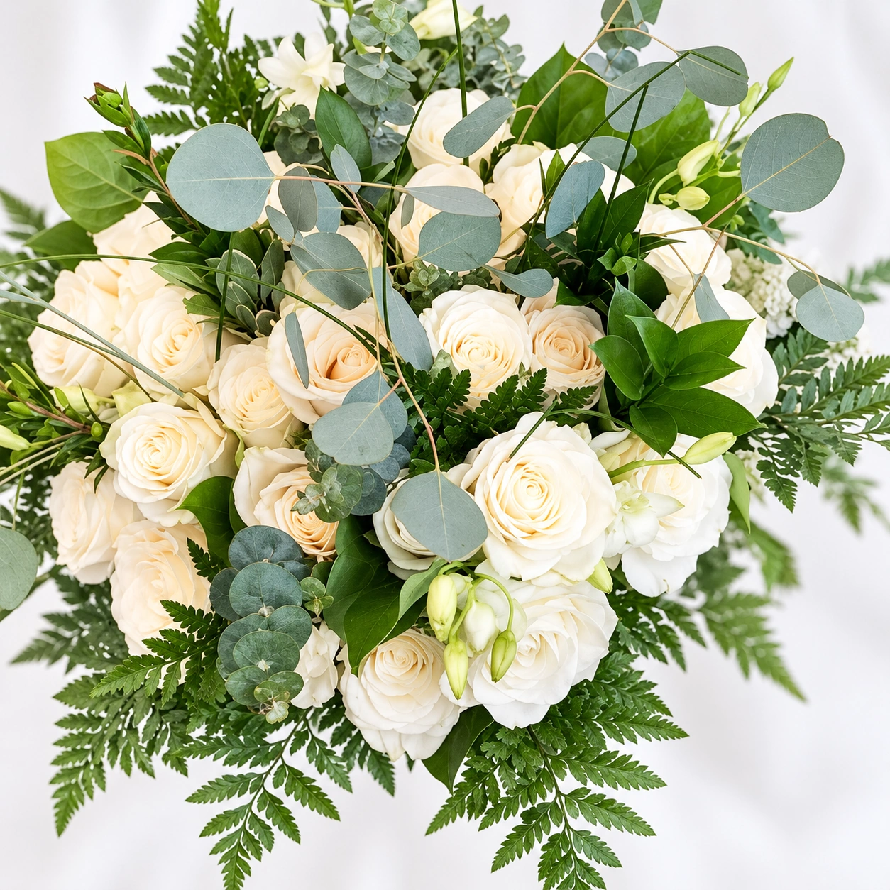 Ivory rose bouquet with eucalyptus and fern foliage against a soft white background